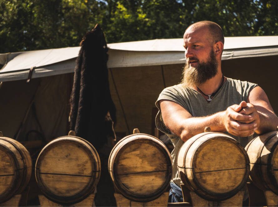 Guest enjoying a whiskey tasting beside oak barrels